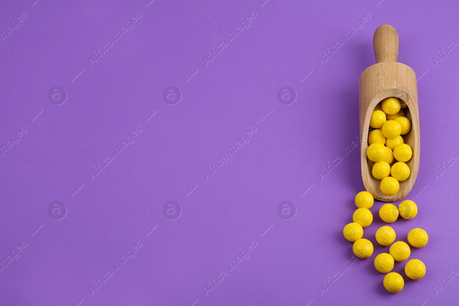 Photo of Delicious lemon chewing gums and scoop on purple background, flat lay. Space for text