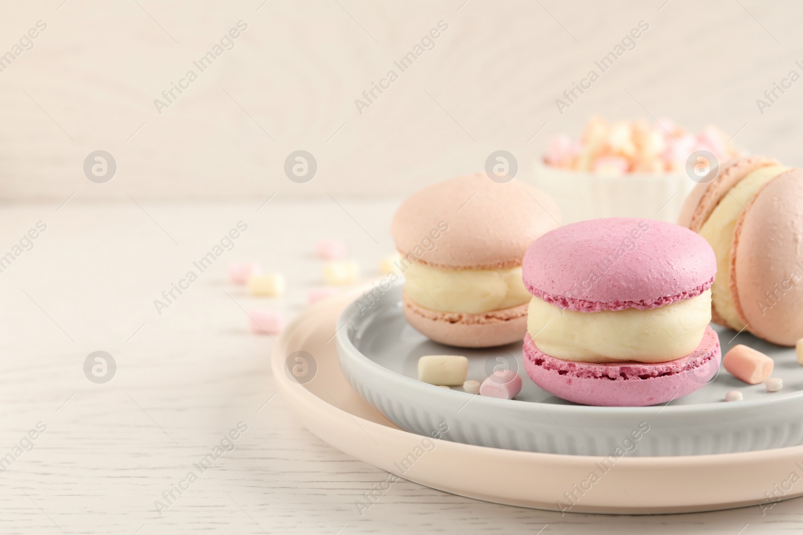 Photo of Delicious colorful macarons and marshmallows on white wooden table, closeup. Space for text