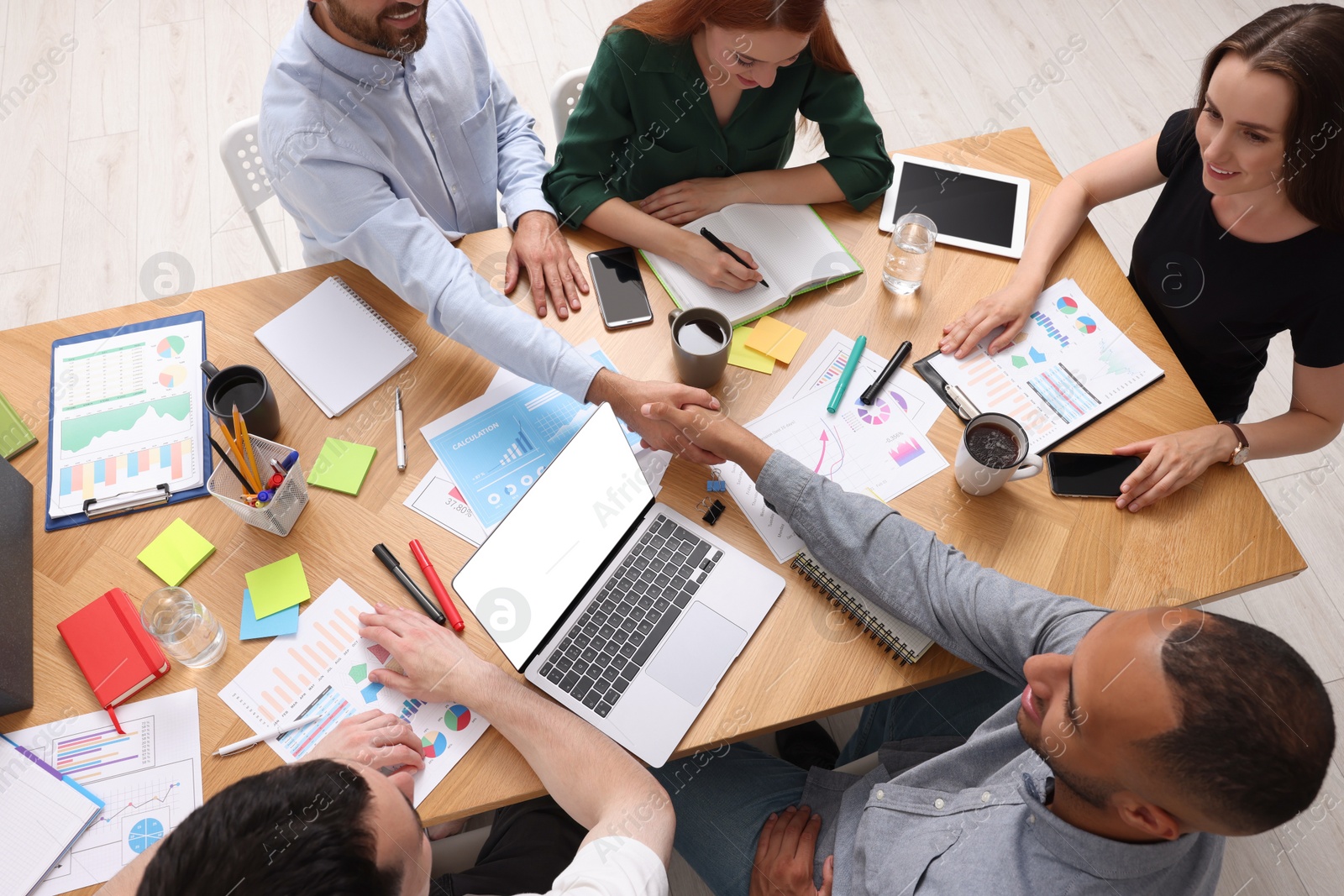 Photo of Team of employees working together at wooden table indoors, above view. Startup project