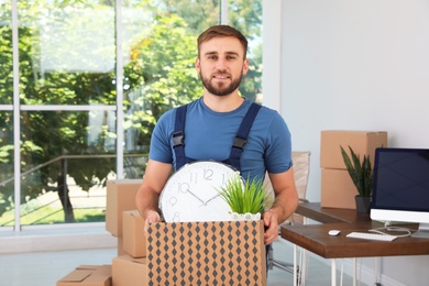 Young worker with box of things in office. Moving service