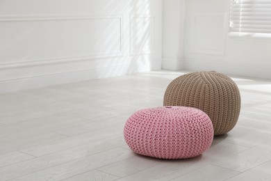 Different stylish poufs in room, space for text