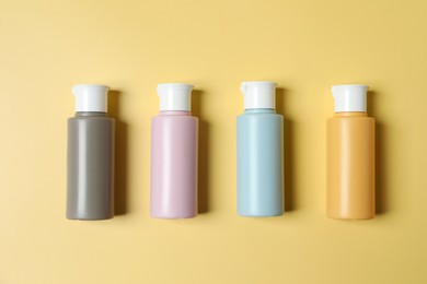 Photo of Cosmetic travel kit. Small containers of personal care products on yellow background, flat lay