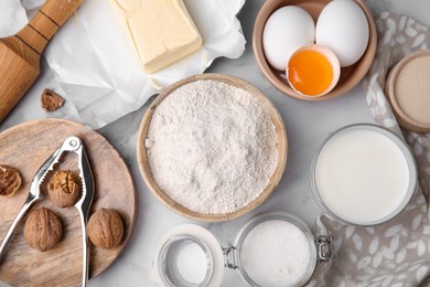 Photo of Bowl of flour and other ingredients in white table, flat lay