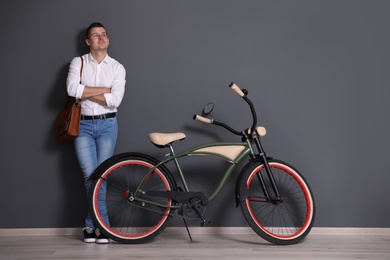 Portrait of handsome young man with bicycle near color wall