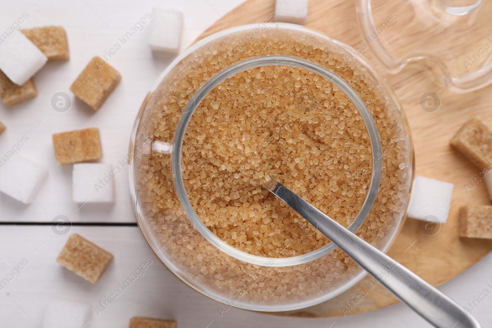 Photo of Jar and spoon with brown sugar on table, top view