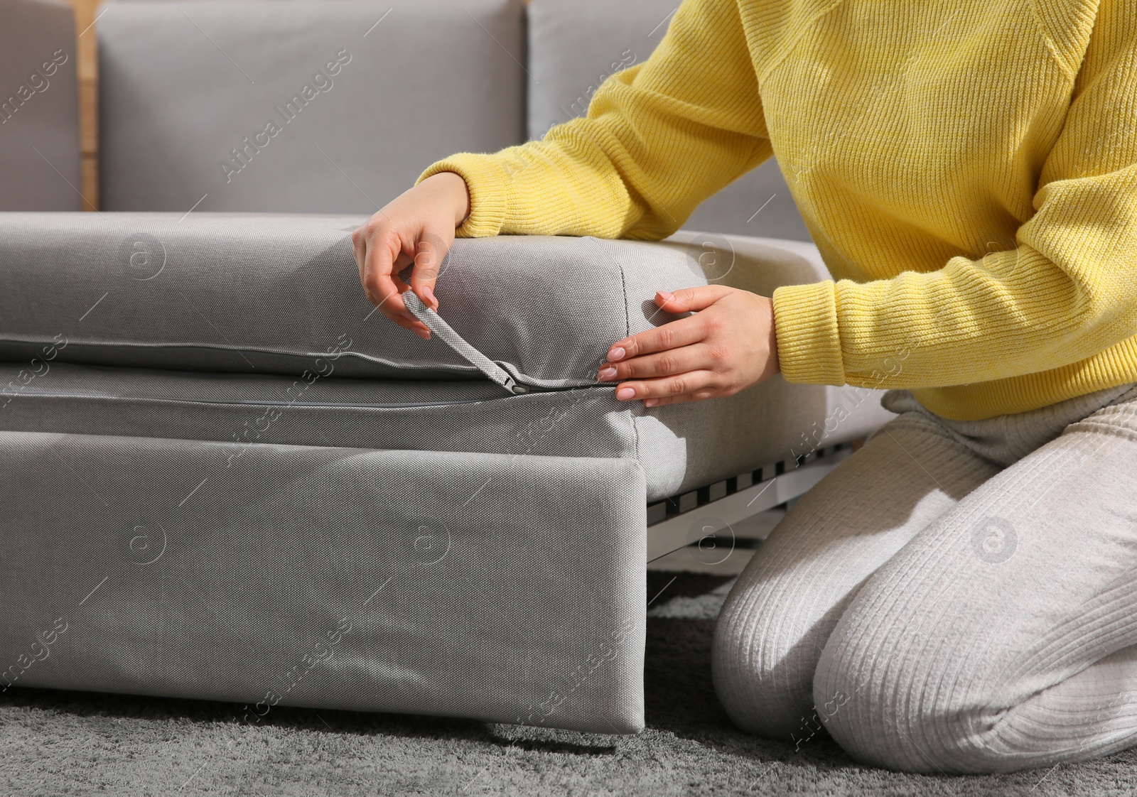 Photo of Young woman unfolding sofa into a bed in room, closeup. Modern interior