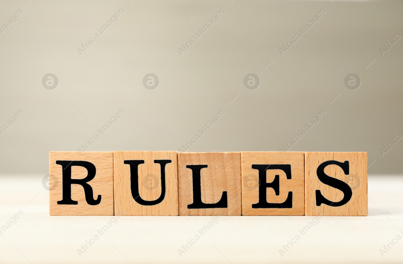 Photo of Word Rules made of cubes with letters on light wooden table