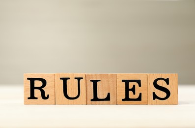 Photo of Word Rules made of cubes with letters on light wooden table