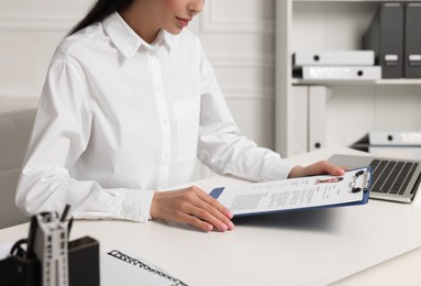 Photo of Human resources manager reading applicant's resume at white table in office, closeup