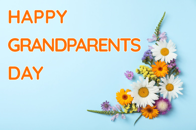 Image of Flat lay composition with wild flowers and phrase HAPPY GRANDPARENTS DAY on light blue background