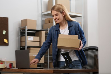 Photo of Seller with parcels and laptop in office. Online store