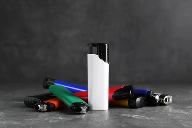 Photo of Stylish small pocket lighters on grey table