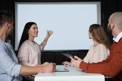 Photo of Business people having meeting in conference room with video projection screen