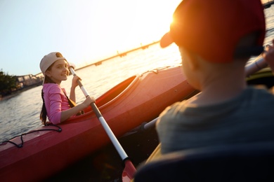 Photo of Children kayaking on river at sunset. Summer camp activity