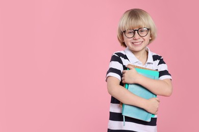 Photo of Cute little boy wearing glasses with books on pink background, space for text