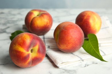 Photo of Fresh juicy peaches, leaves and fabric on marble table