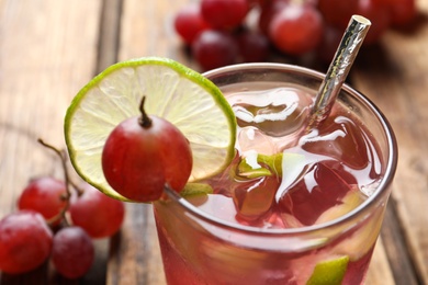 Photo of Soda water with grapes, ice and lime, closeup. Refreshing drink