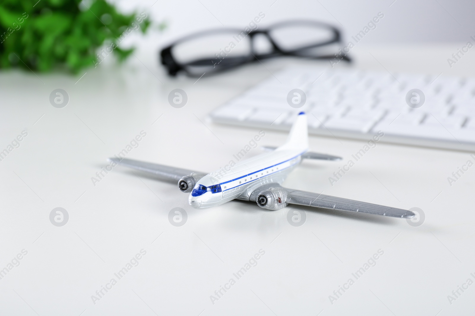 Photo of Composition with airplane model and computer keyboard on table. Travel agency concept