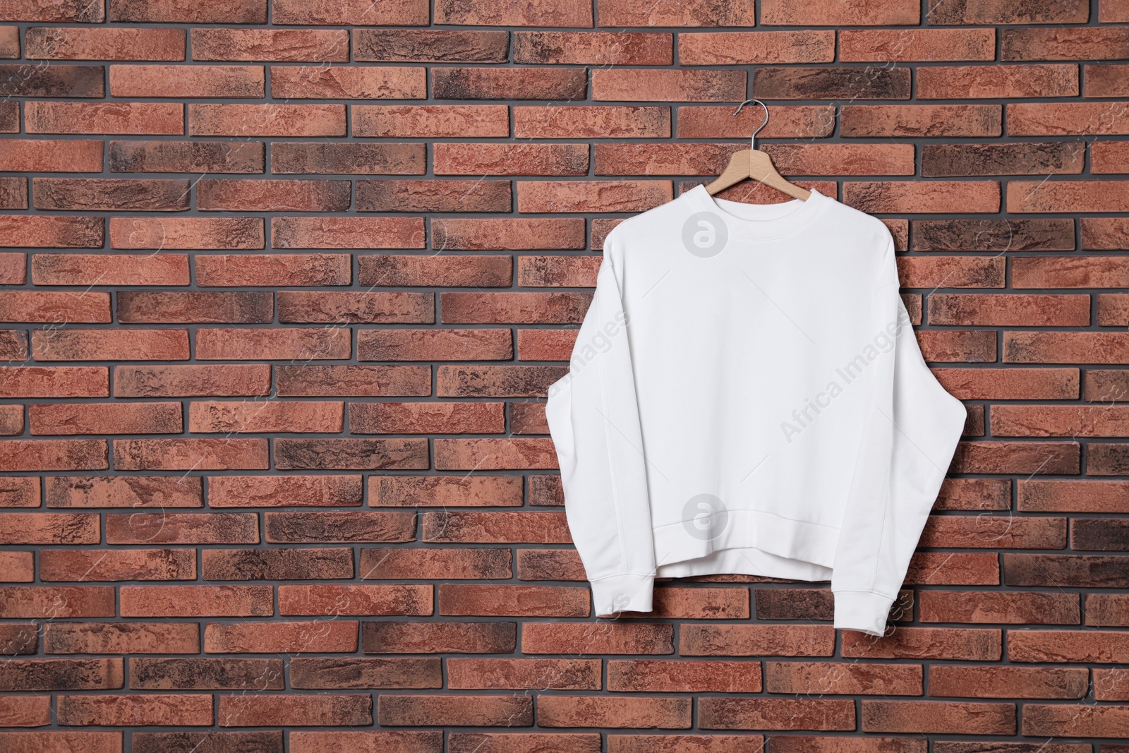 Photo of Hanger with new sweater on brick wall, mock up for design