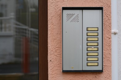 Modern intercom hanging on beige wall outdoors