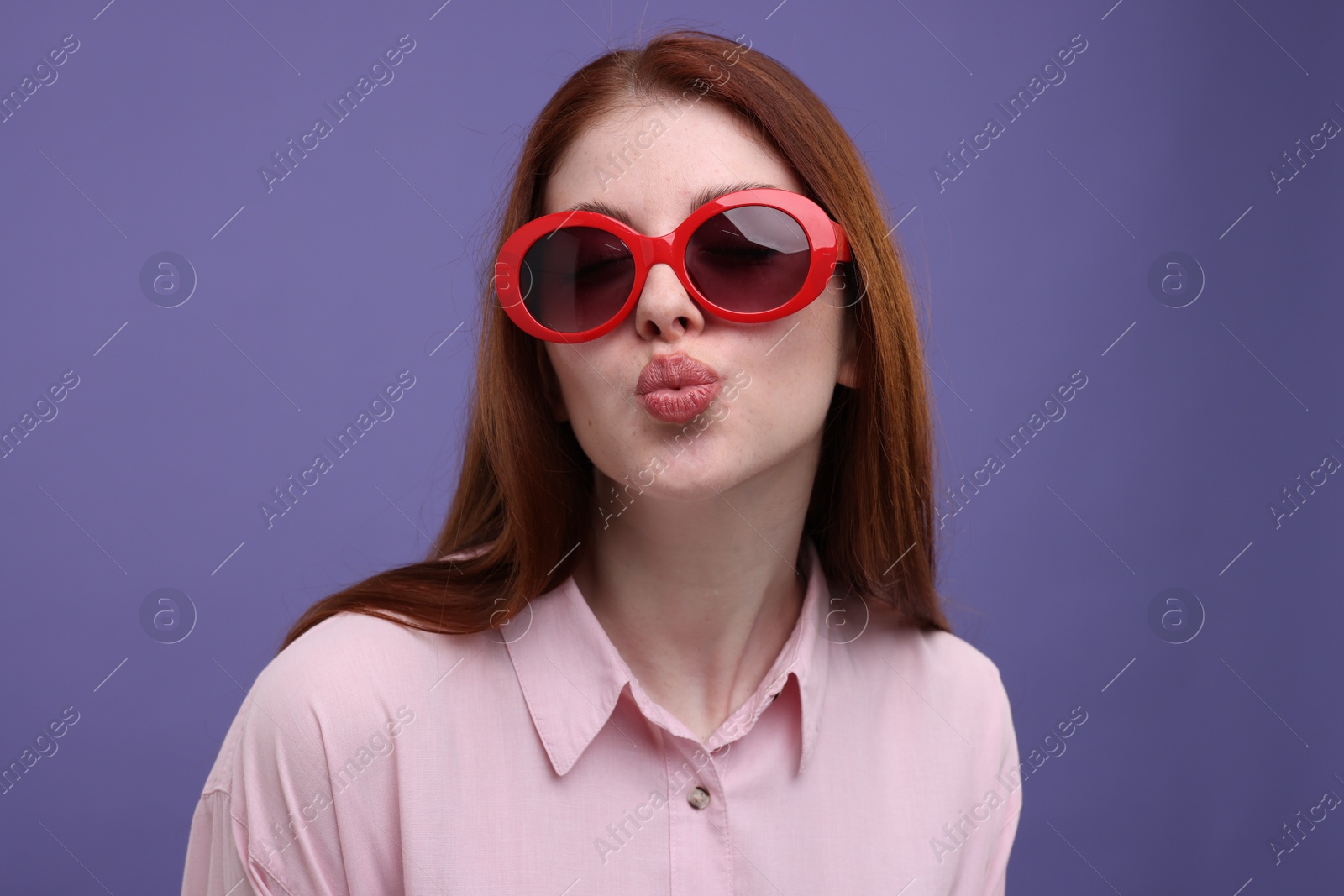 Photo of Portrait of beautiful woman in sunglasses on purple background