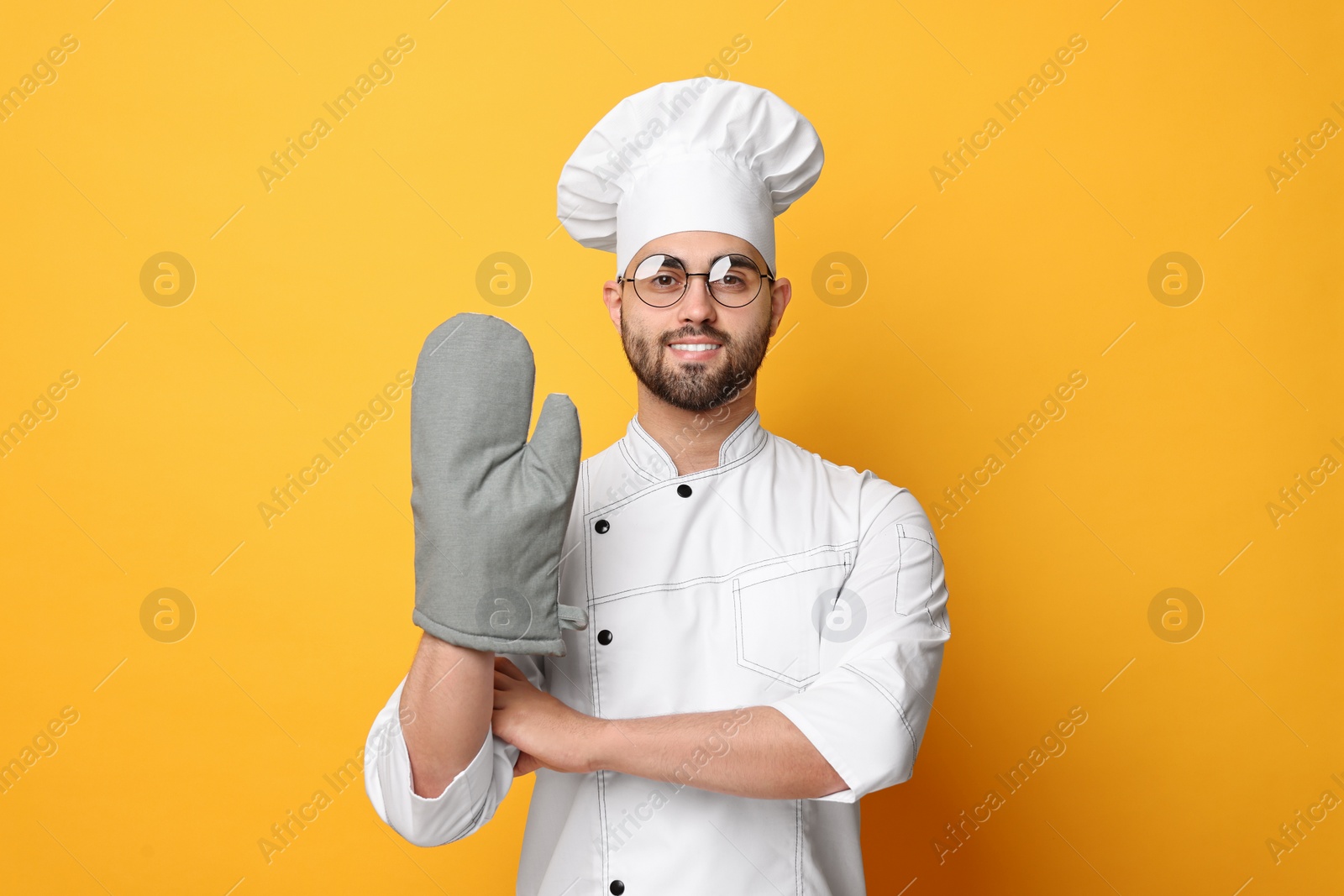 Photo of Professional chef in uniform on yellow background
