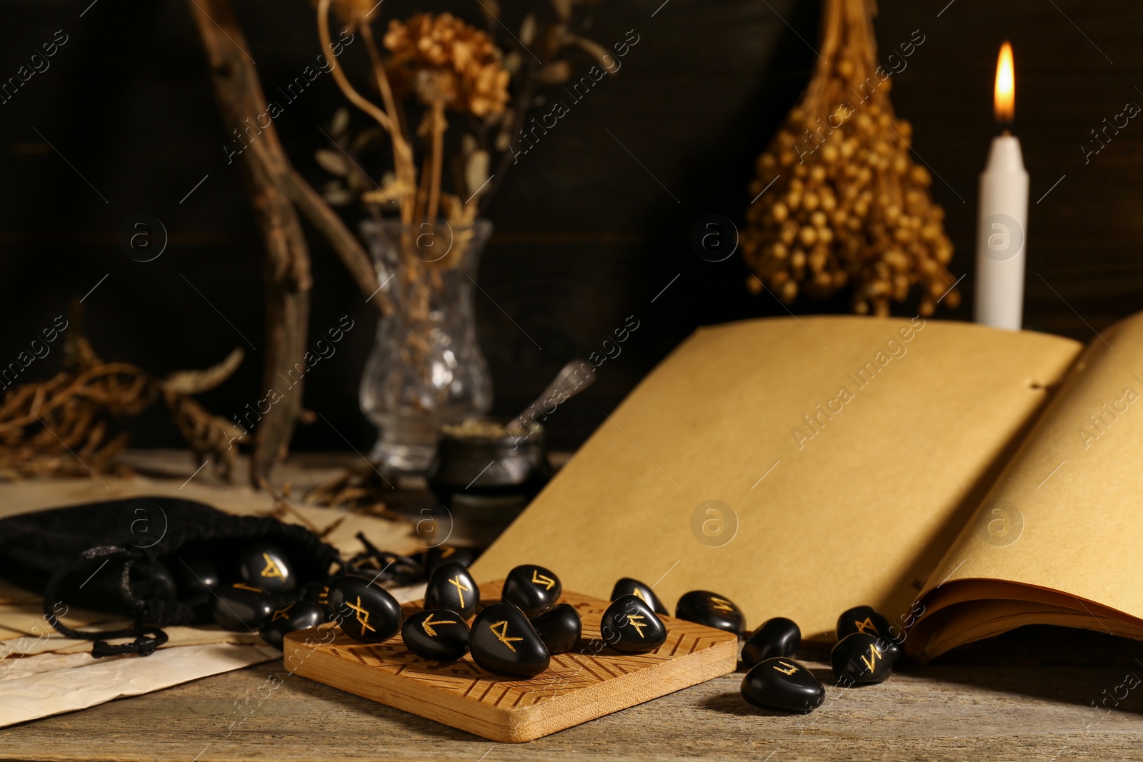 Photo of Composition with black rune stones and old book on wooden table