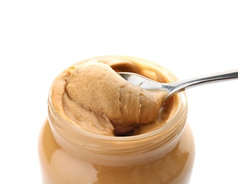 Photo of Jar and spoon with creamy peanut butter on white background