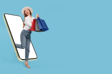 Image of Online shopping. Happy woman with paper bags walking out from smartphone on light blue background, space for text