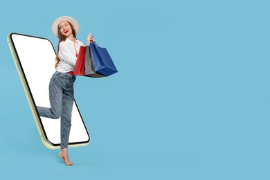 Image of Online shopping. Happy woman with paper bags walking out from smartphone on light blue background, space for text