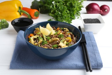 Photo of Stir-fry. Delicious cooked noodles with chicken and vegetables in bowl served on white wooden table