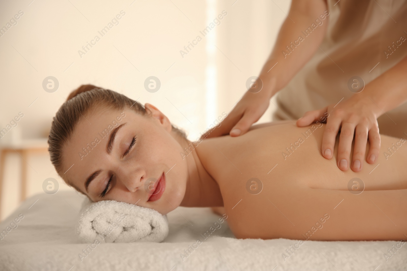 Photo of Young woman receiving back massage in spa salon