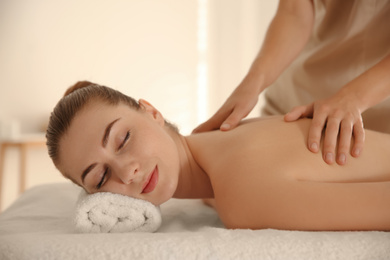 Photo of Young woman receiving back massage in spa salon