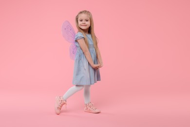 Photo of Cute little girl in fairy costume with violet wings on pink background, space for text