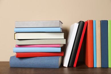 Photo of Many different hardcover books on wooden table near beige wall