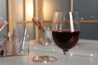 Photo of Glass of red wine against blurred background, closeup. Space for text