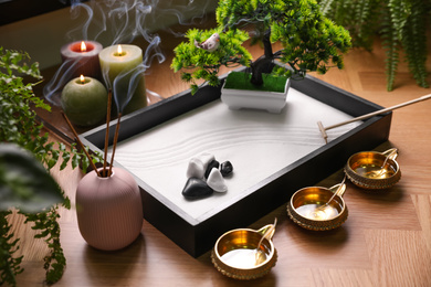 Photo of Beautiful miniature zen garden, incense sticks and oil lamps on table