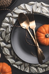 Photo of Autumn table setting with golden cutlery and pumpkins on black background, flat lay