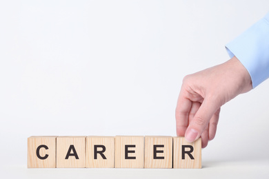 Photo of Woman making word CAREER with wooden cubes on white background, closeup