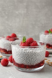 Photo of Delicious chia pudding with raspberries and mint on light marble table, space for text