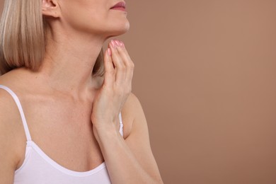 Photo of Woman touching her neck on beige background, closeup. Space for text