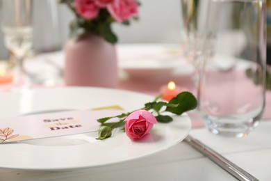 Photo of Romantic table setting. Plate with pink rose on table, closeup