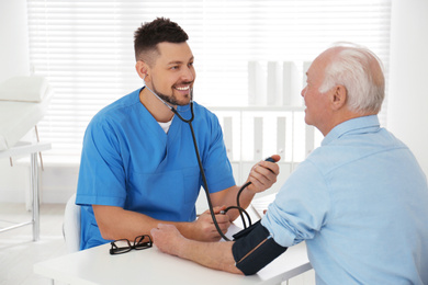 Photo of Doctor measuring blood pressure of senior patient in office