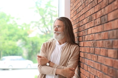 Photo of Handsome mature man standing near brick wall