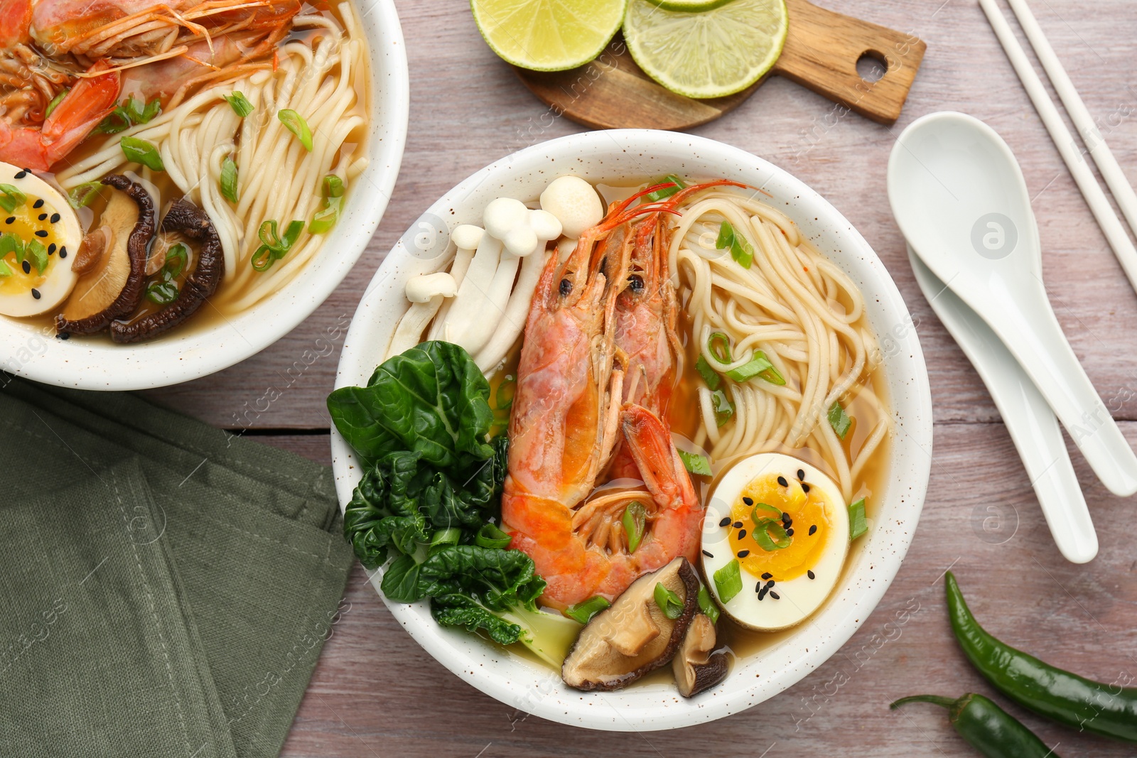 Photo of Delicious ramen with shrimps in bowls served on wooden table, flat lay. Noodle soup