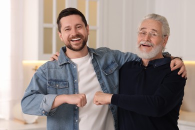 Photo of Happy son and his dad making fist bump at home