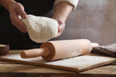 Photo of Man making dough at wooden table, closeup