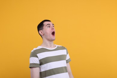 Portrait of surprised man on orange background, space for text