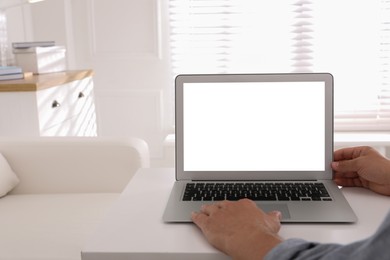 Photo of Man with modern laptop at white table indoors, closeup. Space for design