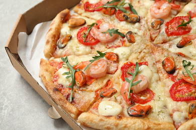 Photo of Delicious seafood pizza in box on table, closeup